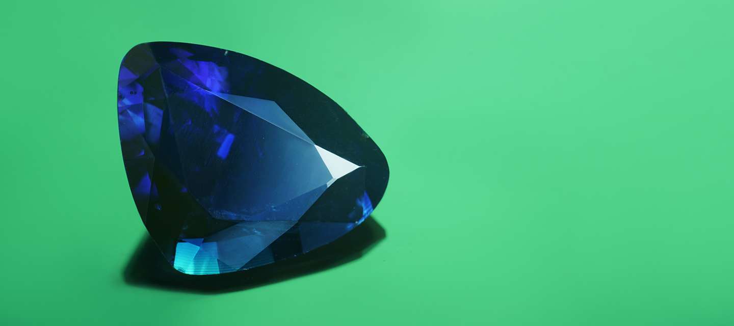 Trilliant cut blue sapphire on green background