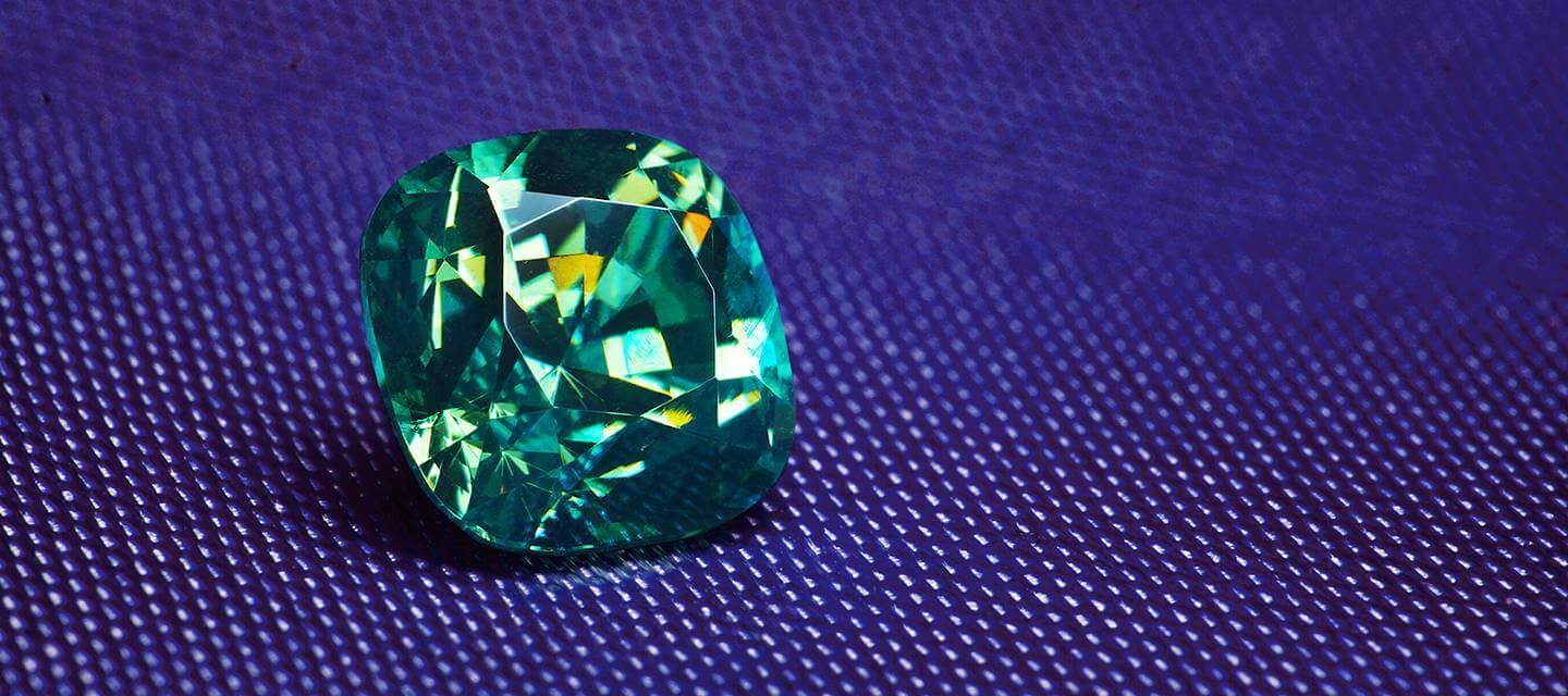 Demantoid green garnet on a blue textured background