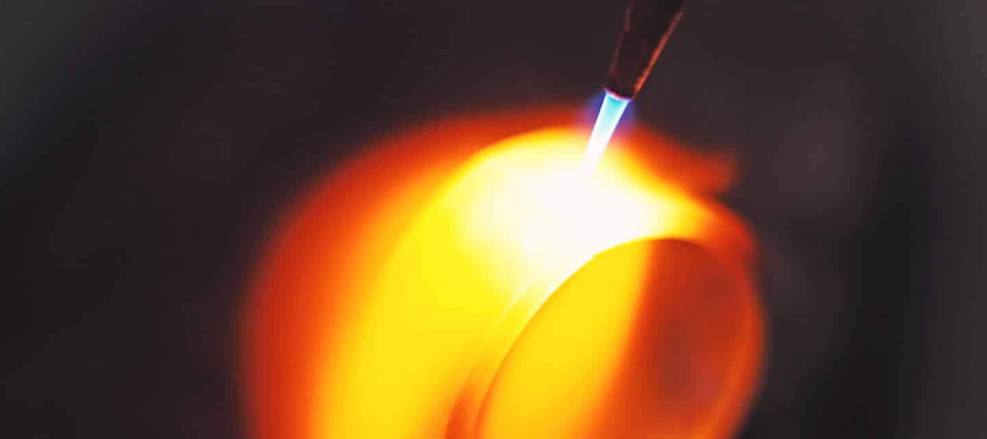 Wedding ring being heated by blowtorch on dark background