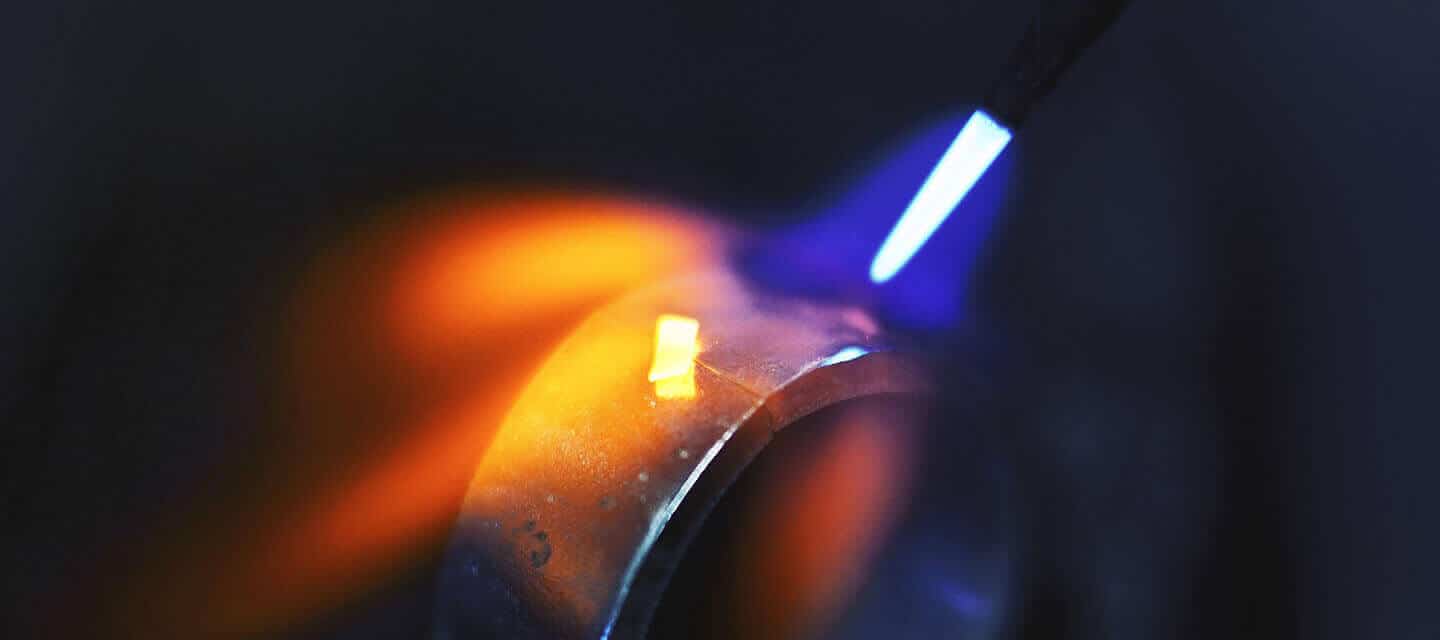 Closeup of soldering wedding ring on dark background