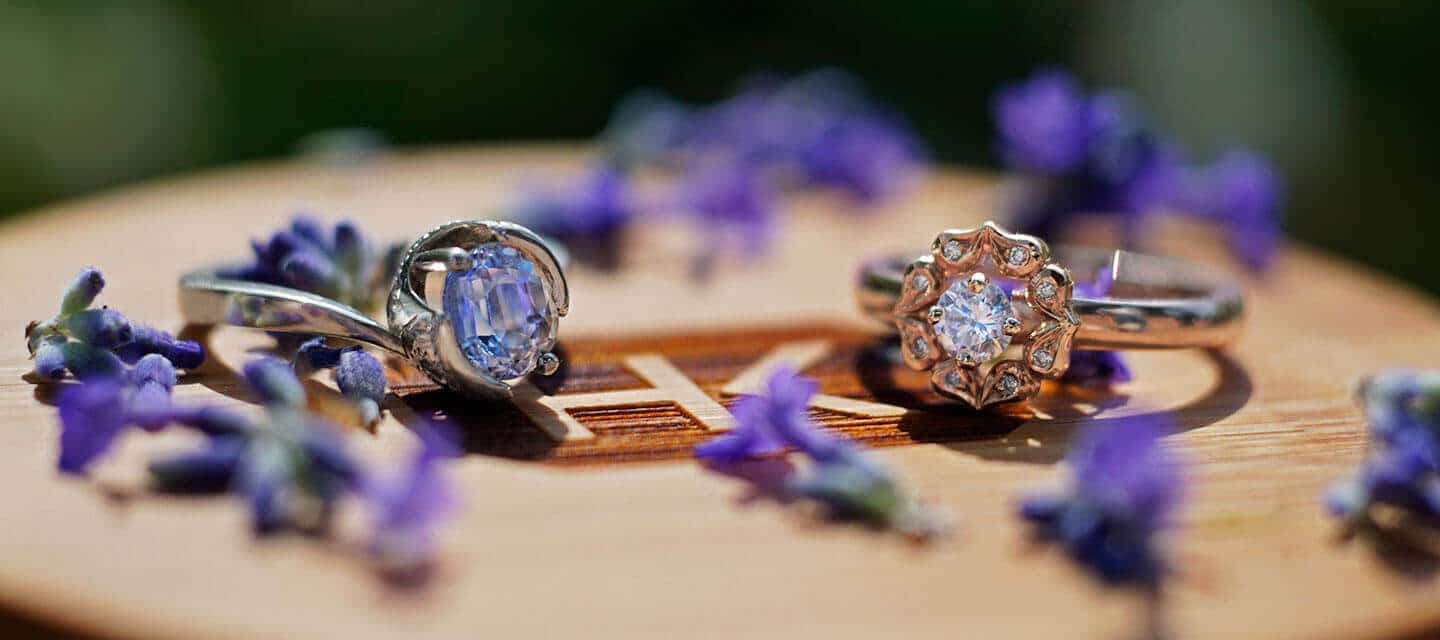 Engagement rings on bamboo box surrounded by purple flowers