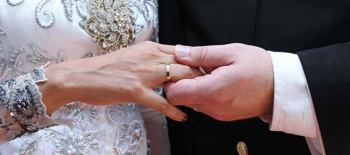 Closeup of couple holding hands at wedding