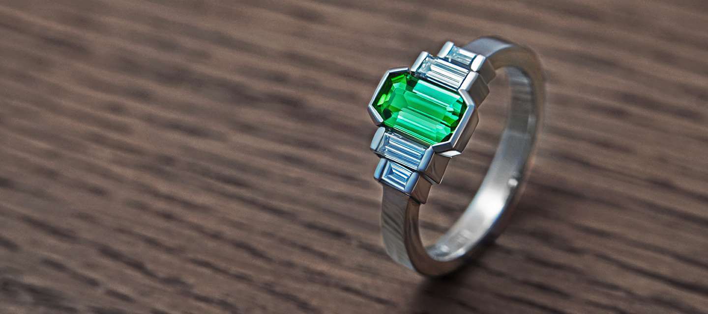 Green tourmaline and diamond ring on table