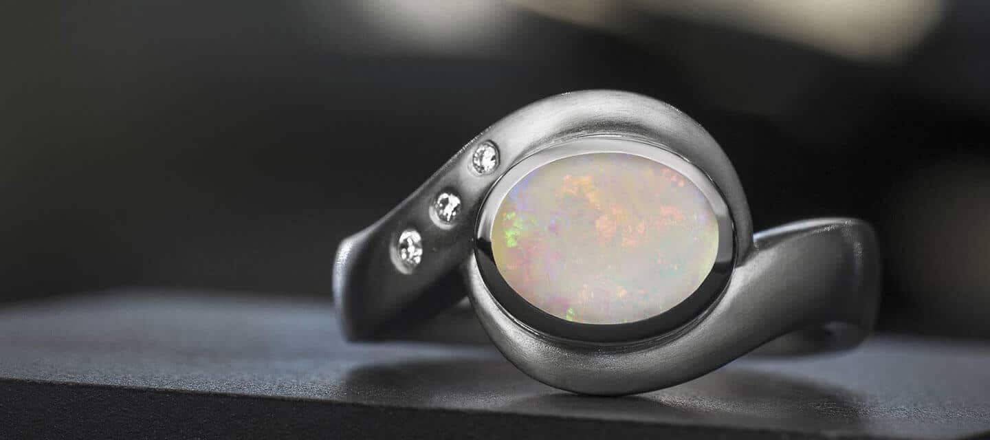 Ring with sweeping arms surrounding opal