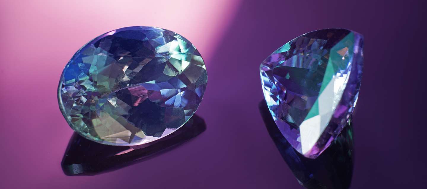 2 tanzanite gemstones on purple background