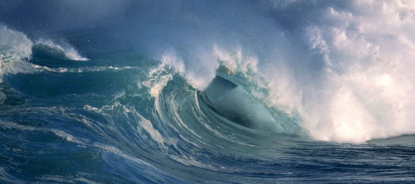 Crest of crashing waves against sky