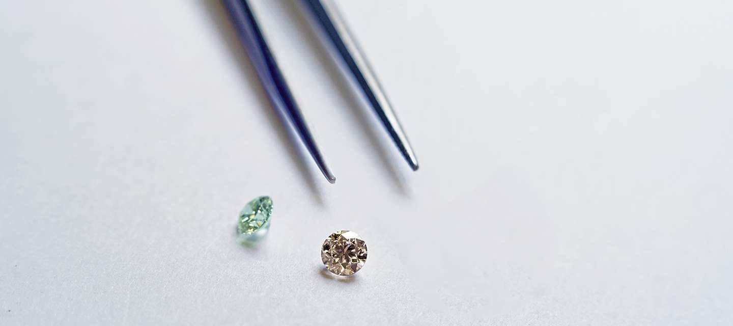 Heat treated diamonds lay in next to tweezers