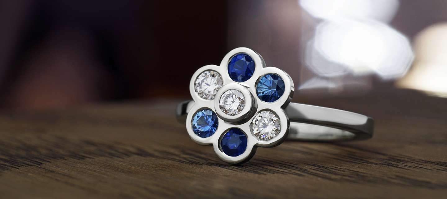 Flower inspired engagement ring with diamond and blue coloured gemstones