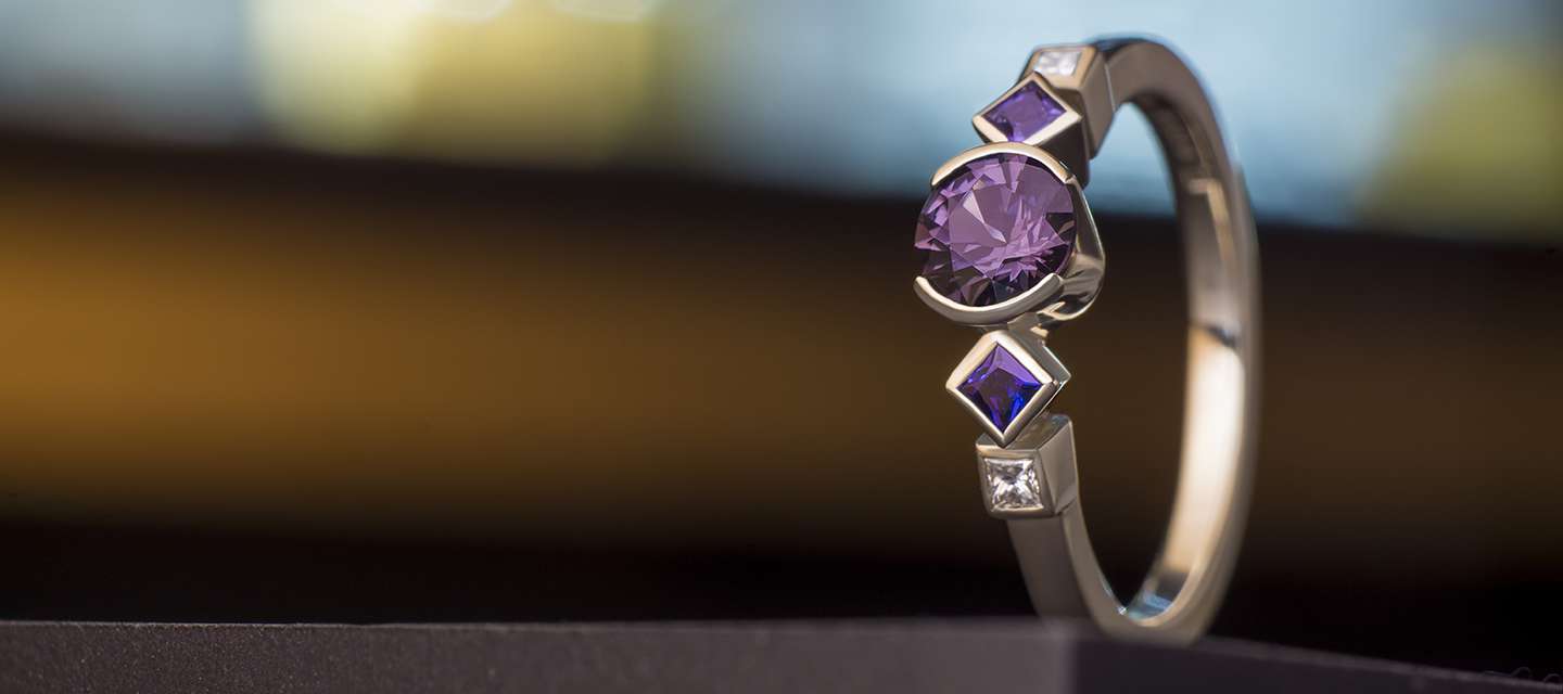 Engagement ring with central and side purple spinel