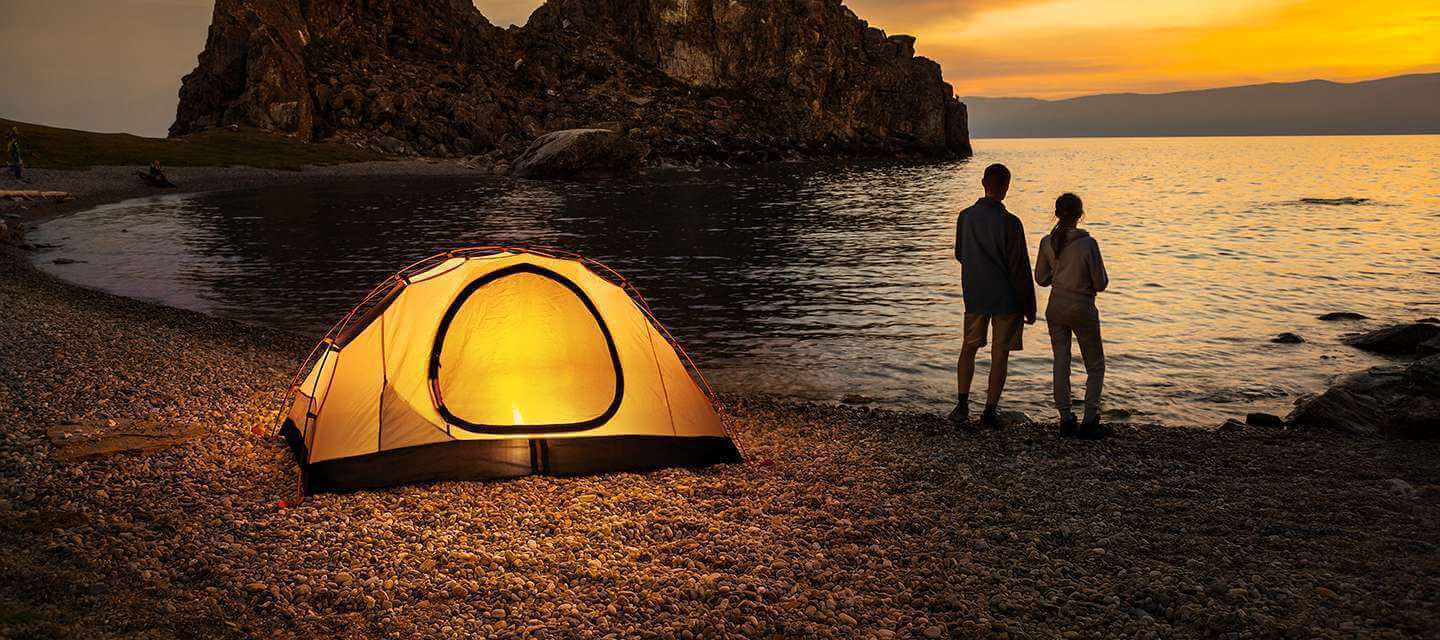 Couple near tent on a sunset beach