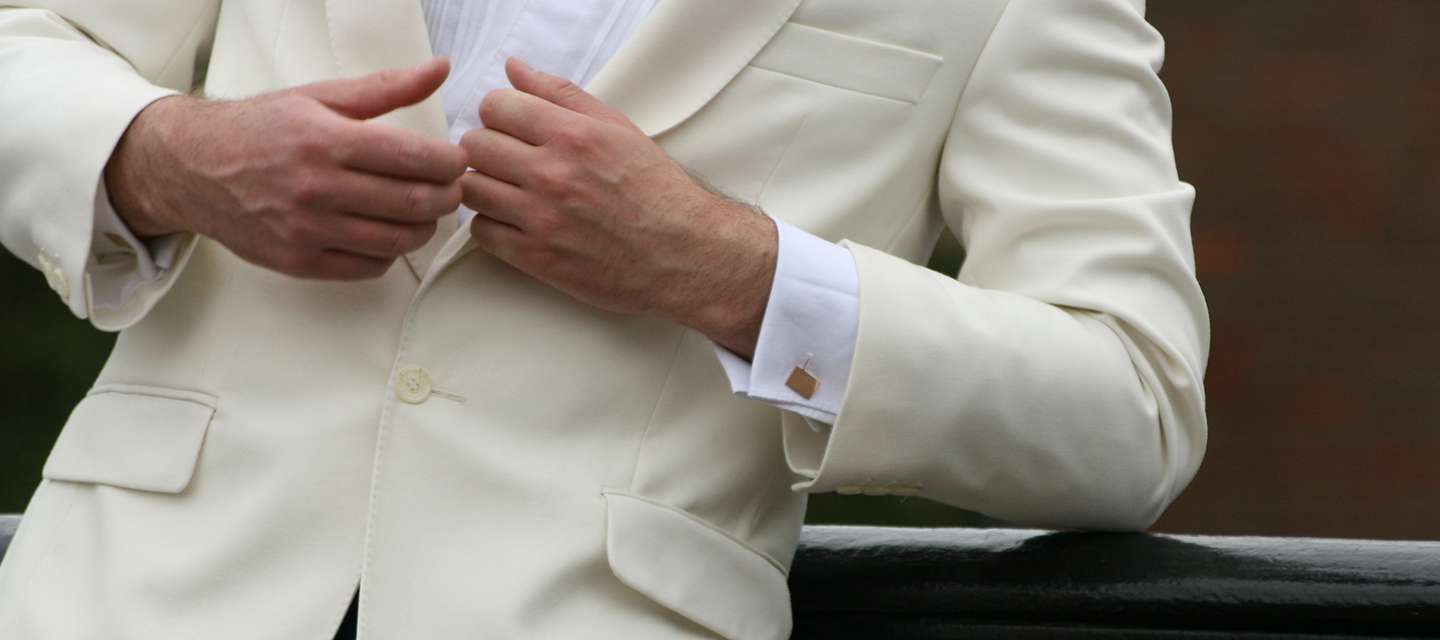 Man in white suit showcasing cufflinks