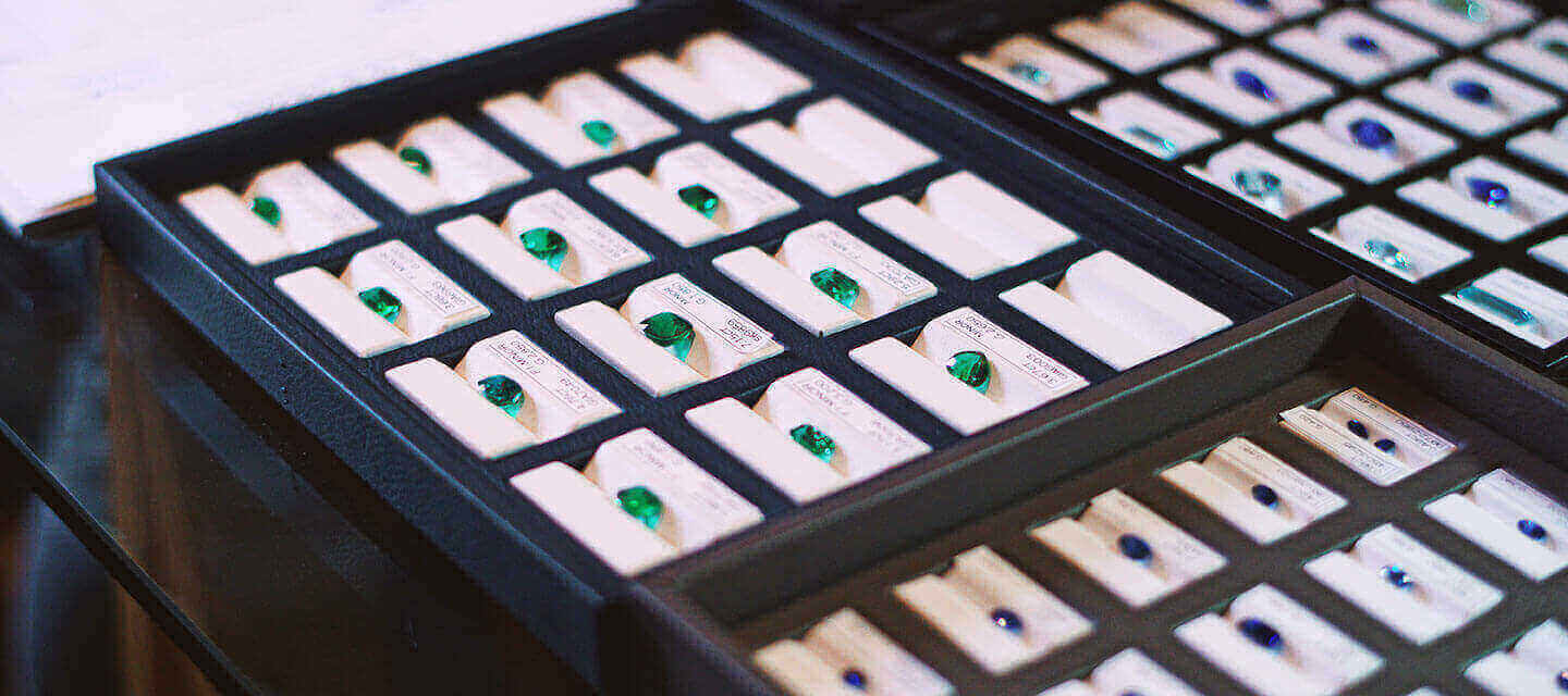 Coloured gemstones in individual boxes displayed on a tray