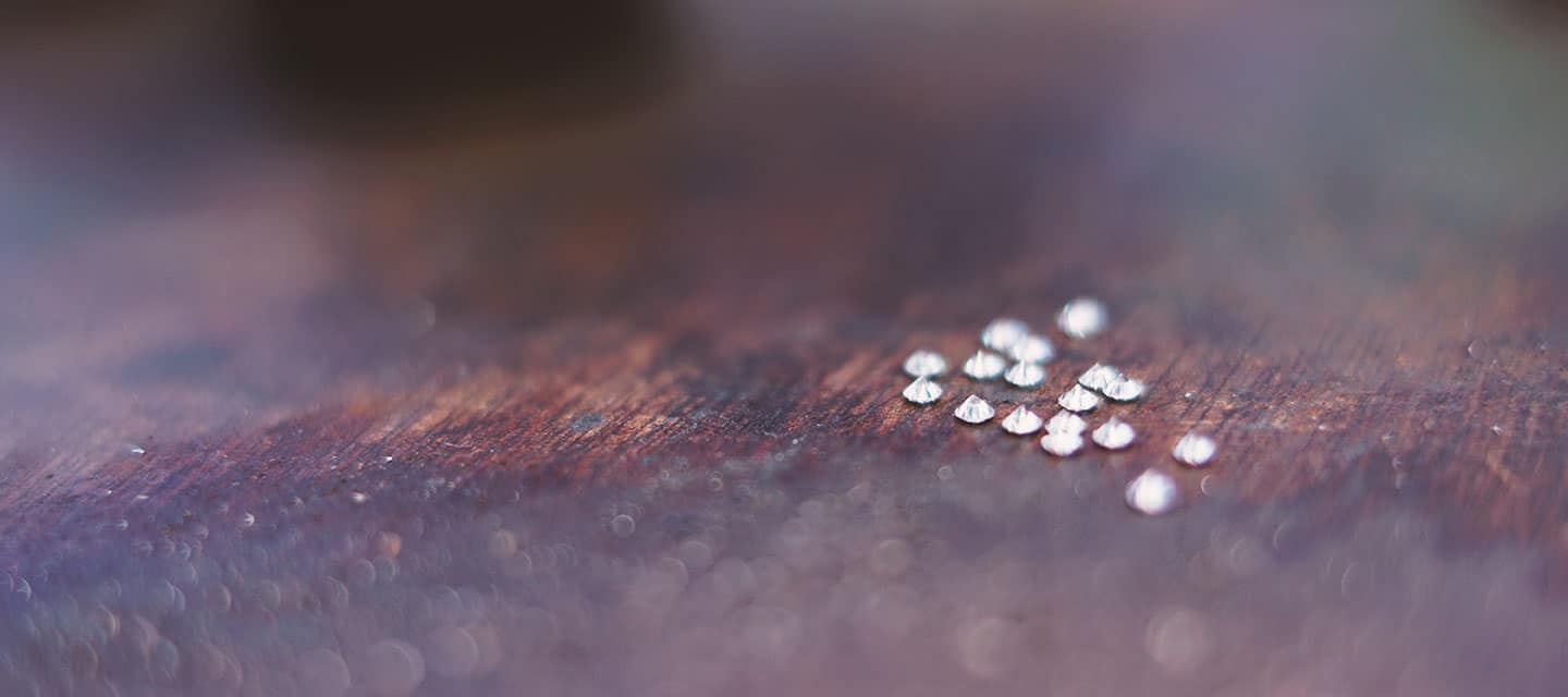 Multiple small diamonds lay on wooden surface