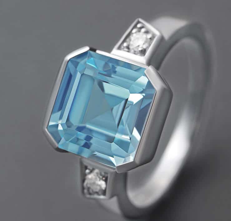 octagonally cut blue topaz in a diamond trilogy ring close up