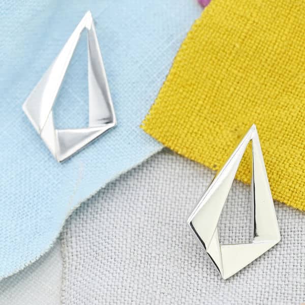 overlapping origami shaped diamond shaped silver earrings on cloth