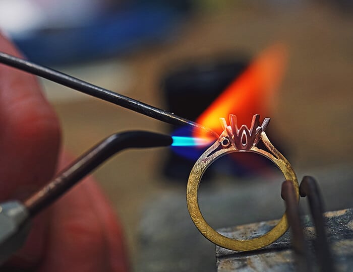 An engagement ring being crafted at a jewellery bench