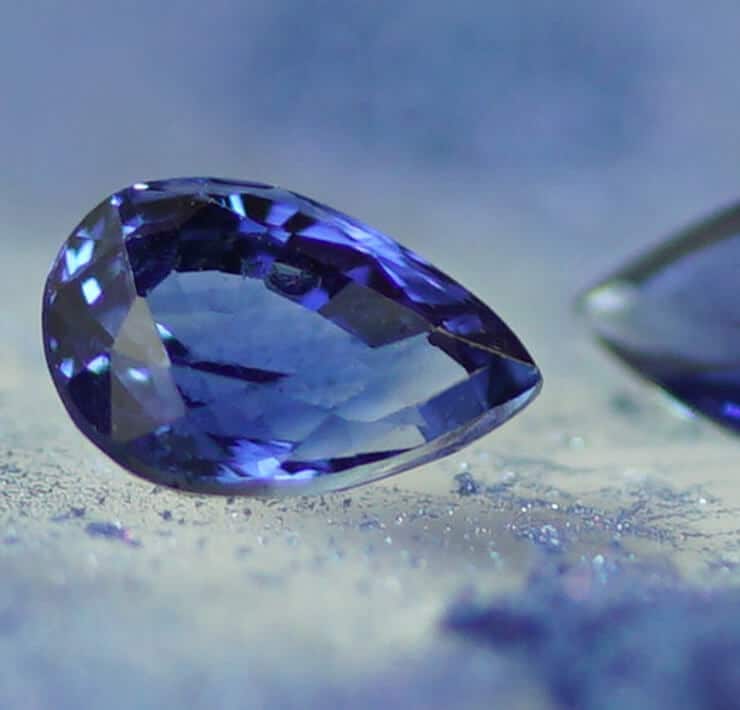 pair of oval blue sapphires on blue powder background