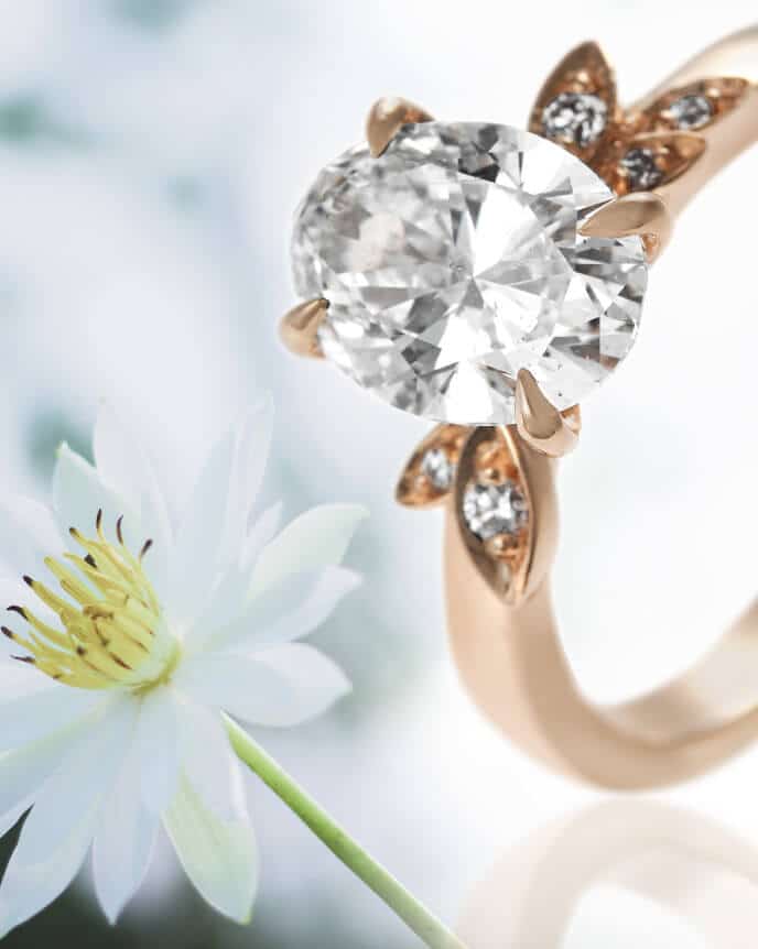 oval diamond ring with leaf shapes and white flower