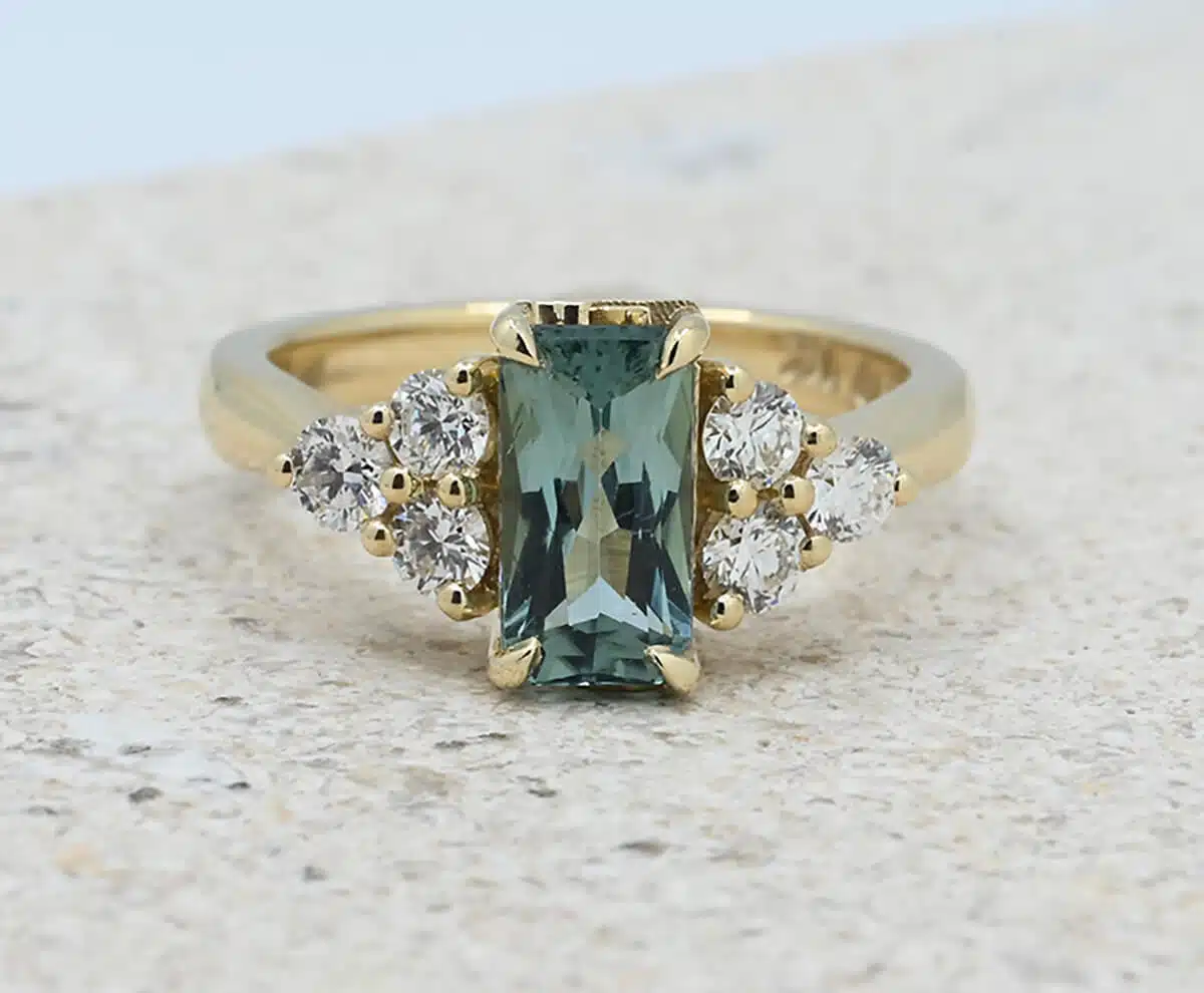 Central teal tourmaline with side diamond gold engagement ring