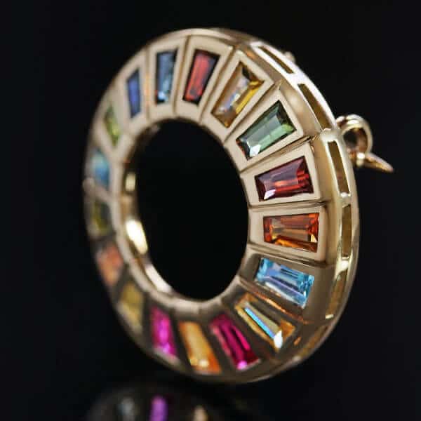 round gold brooch with array of multicoloured gemstones