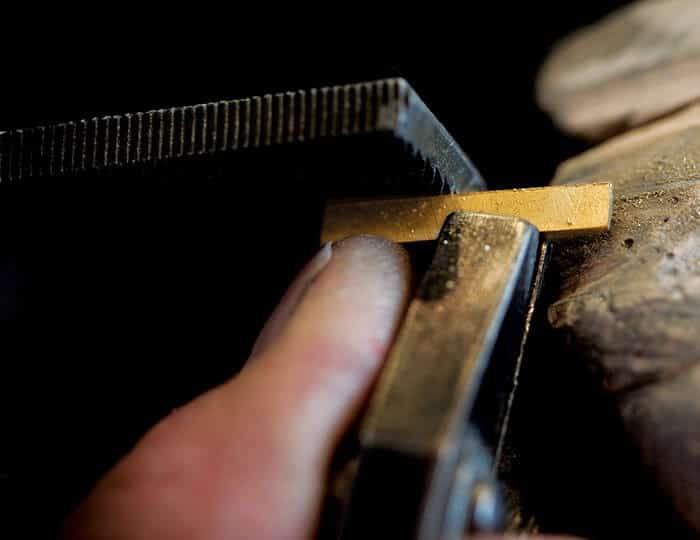 filing gold sheet by hand close up