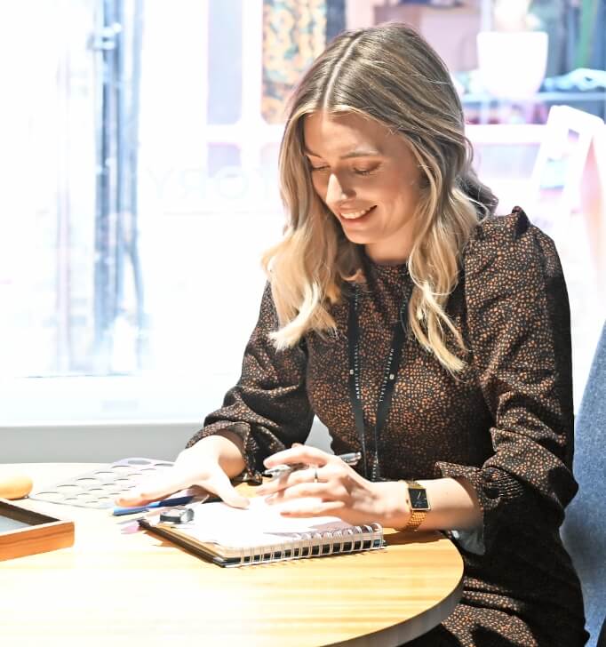 Jewellery designer sketching at a table, smiling