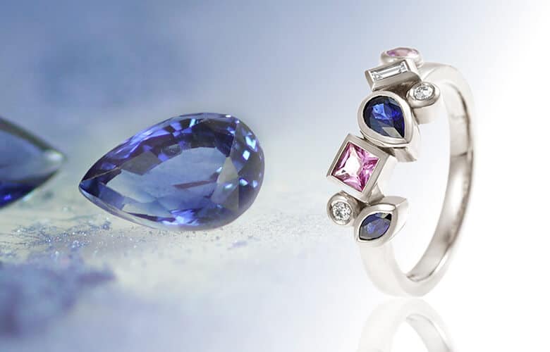 Pink and blue sapphire eternity ring with two blue sapphire loose gemstones