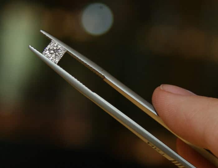 loose princess cut diamond in tweezers