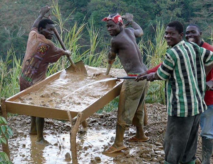 group of artisan gemstone miners with tray of silt