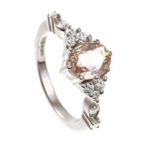 Oval peach gemstone and diamonds in white metal ring