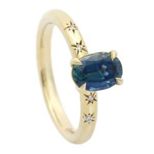 Gold ring with oval teal sapphire and stars