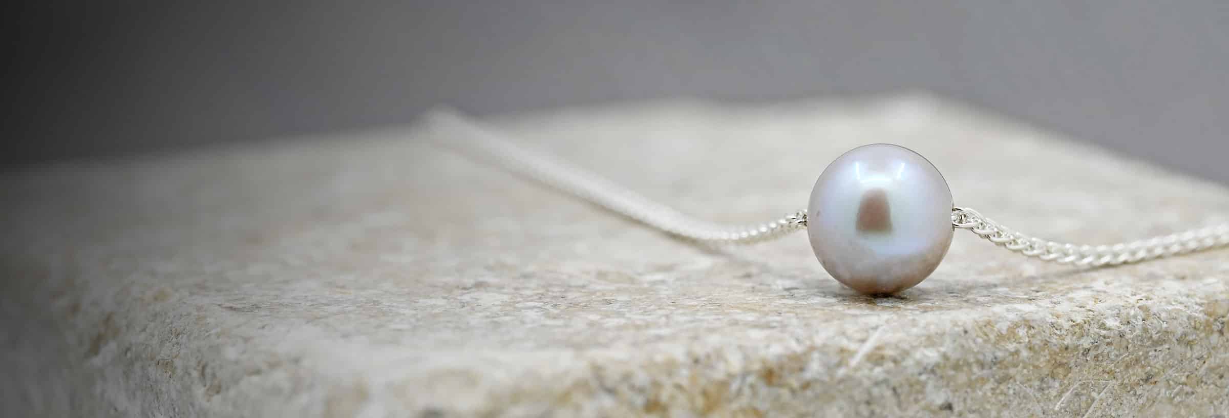 Single pearl on white metal chain