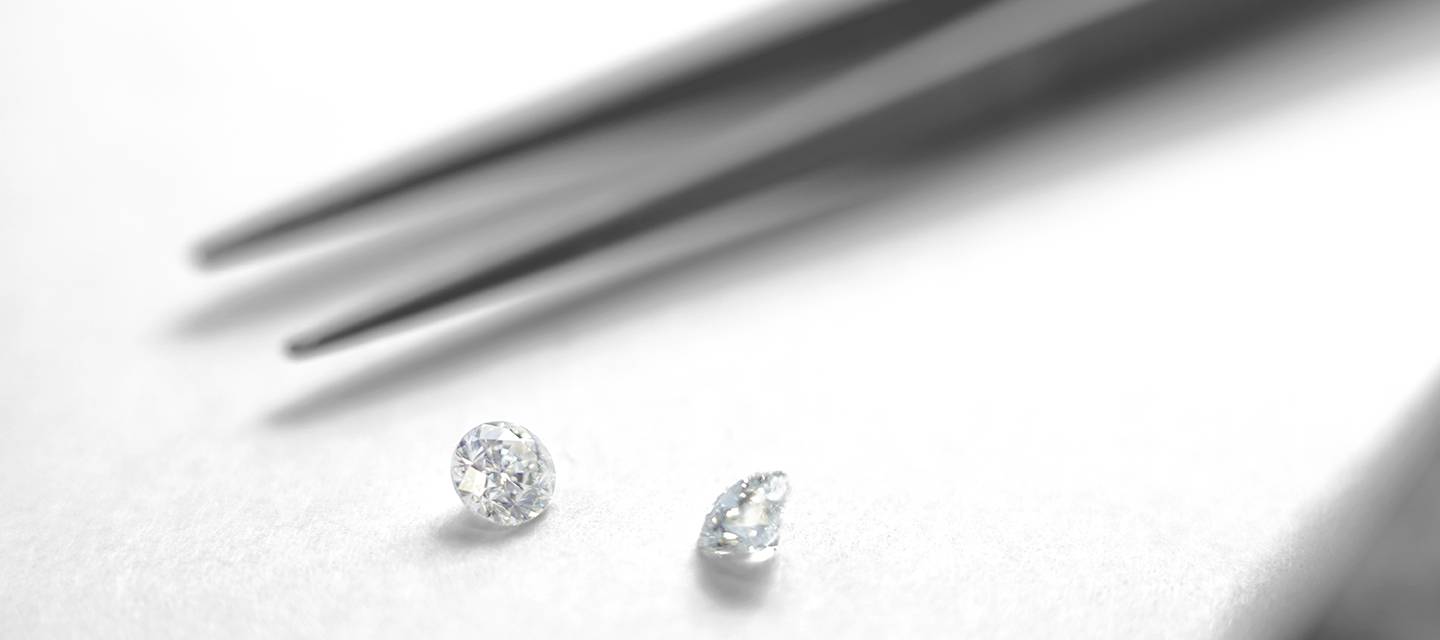 Diamonds and metal tweezers on white surface