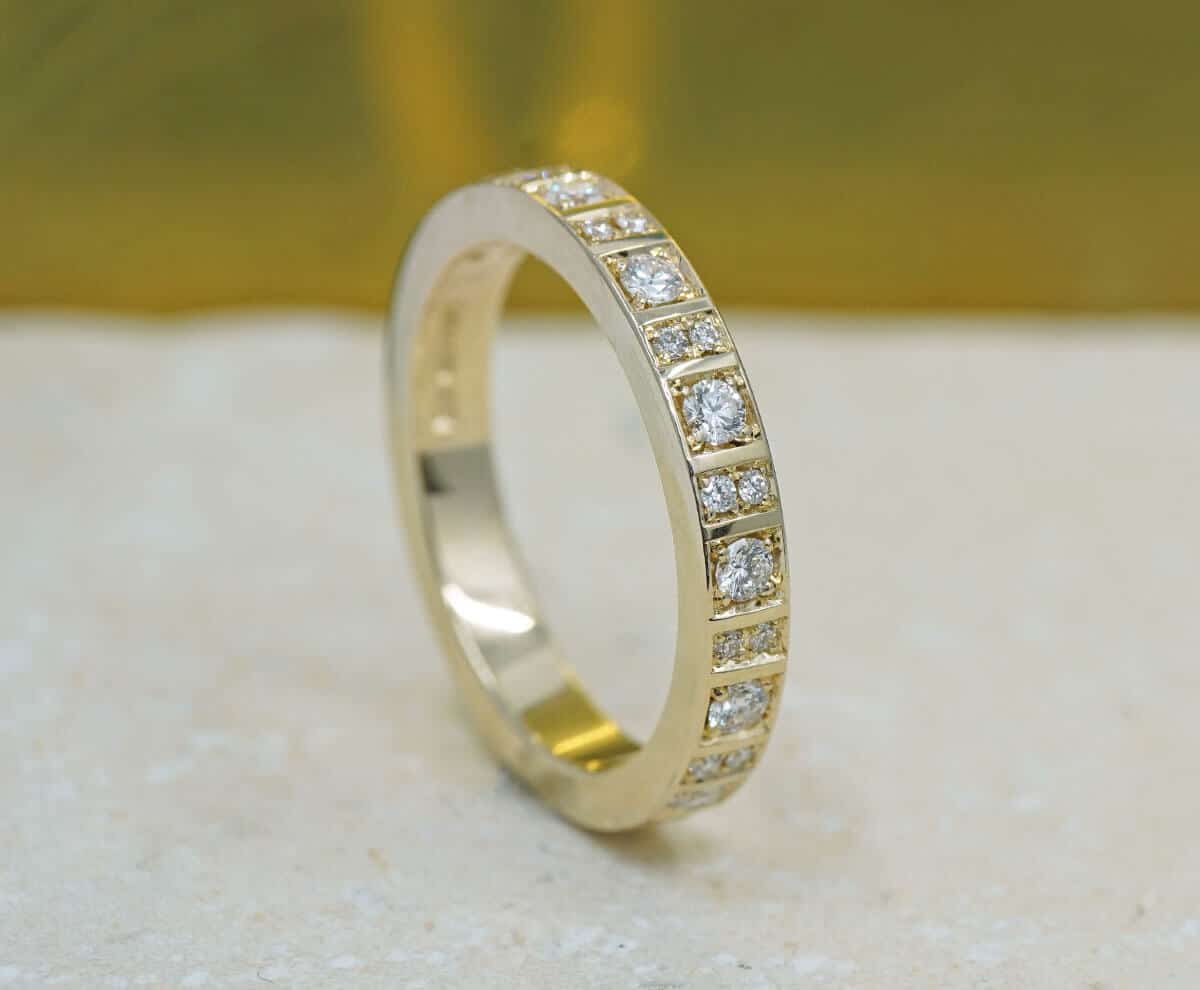 Diamond-set wedding ring with intricate detailing, elegantly displayed on a soft, neutral background