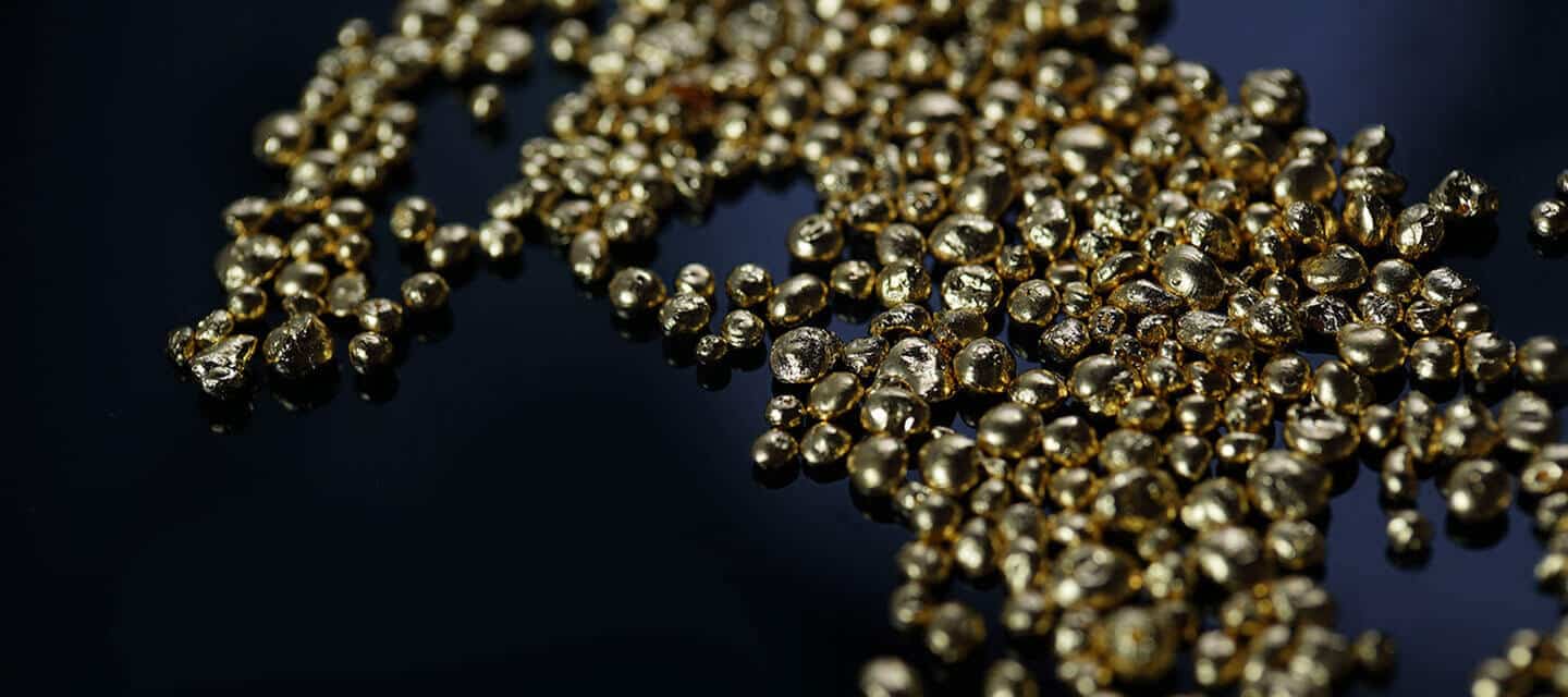 Scattered gold nuggets on black surface