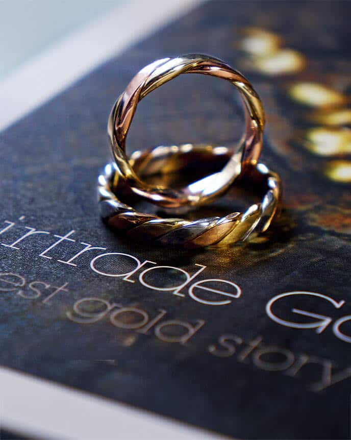 pair of fairtrade wedding rings with twist design on book