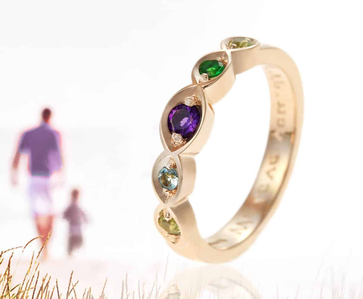 Family birthstone eternity ring set against a serene beach backdrop, symbolising love and connection