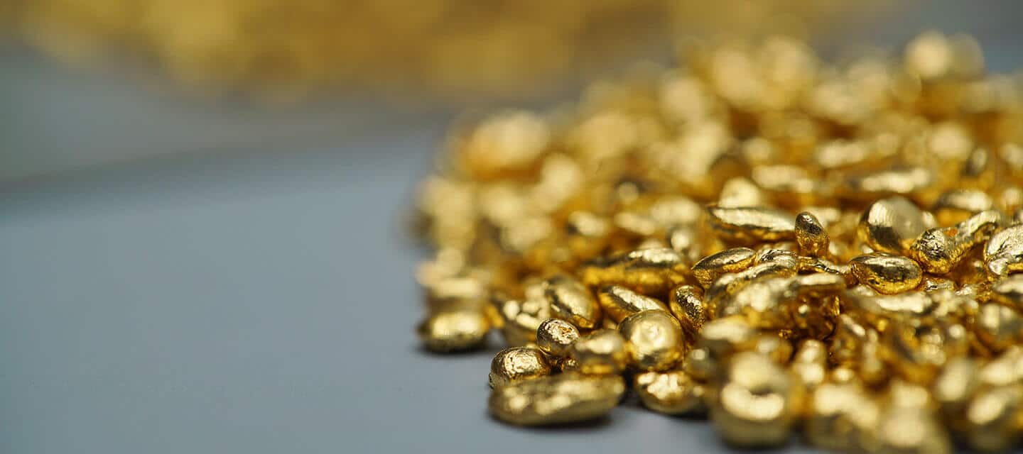 Pile of gold nuggets on grey surface