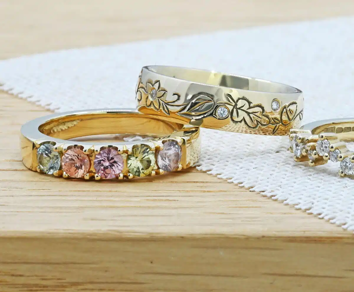 Group of three gemstone eternity rings on a table