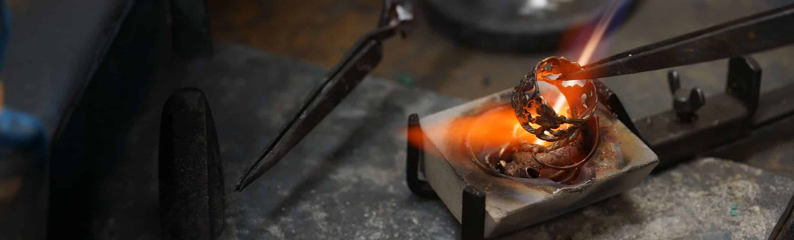 intricate ring held over flame in workshop