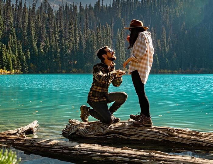 Man Proposing to a Woman by an Aqua Lake in Forested Mountains