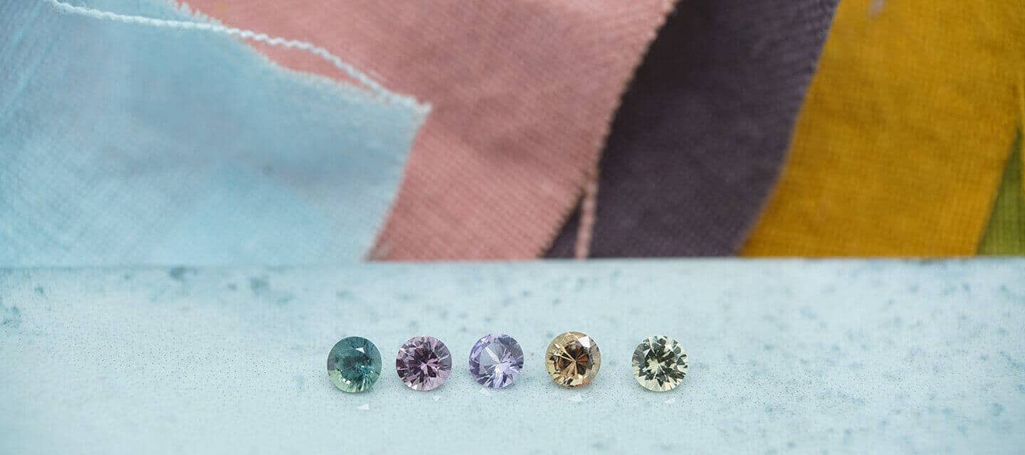 Row of colourful sapphires with fabric swatches in the background