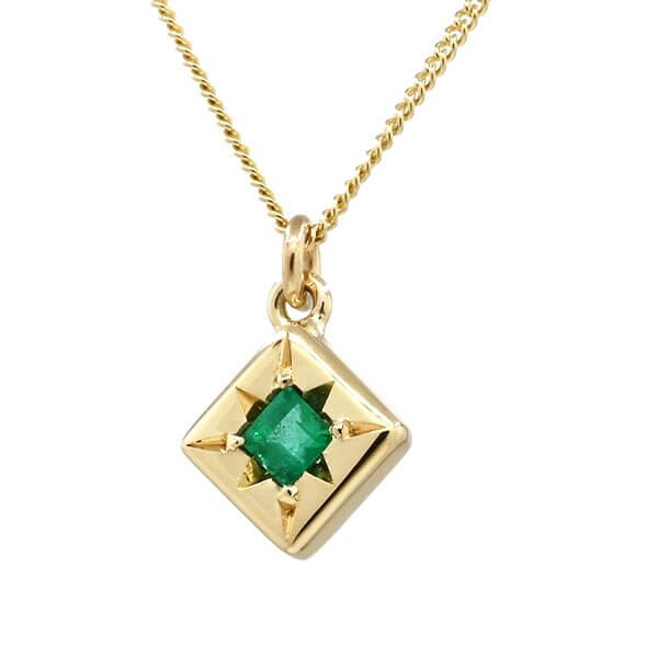 gold engraved pendant with central emerald