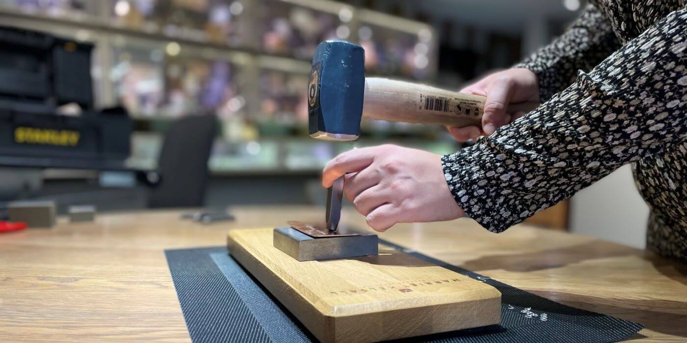 Workshop stamping metal peg onto metal plate with hammer