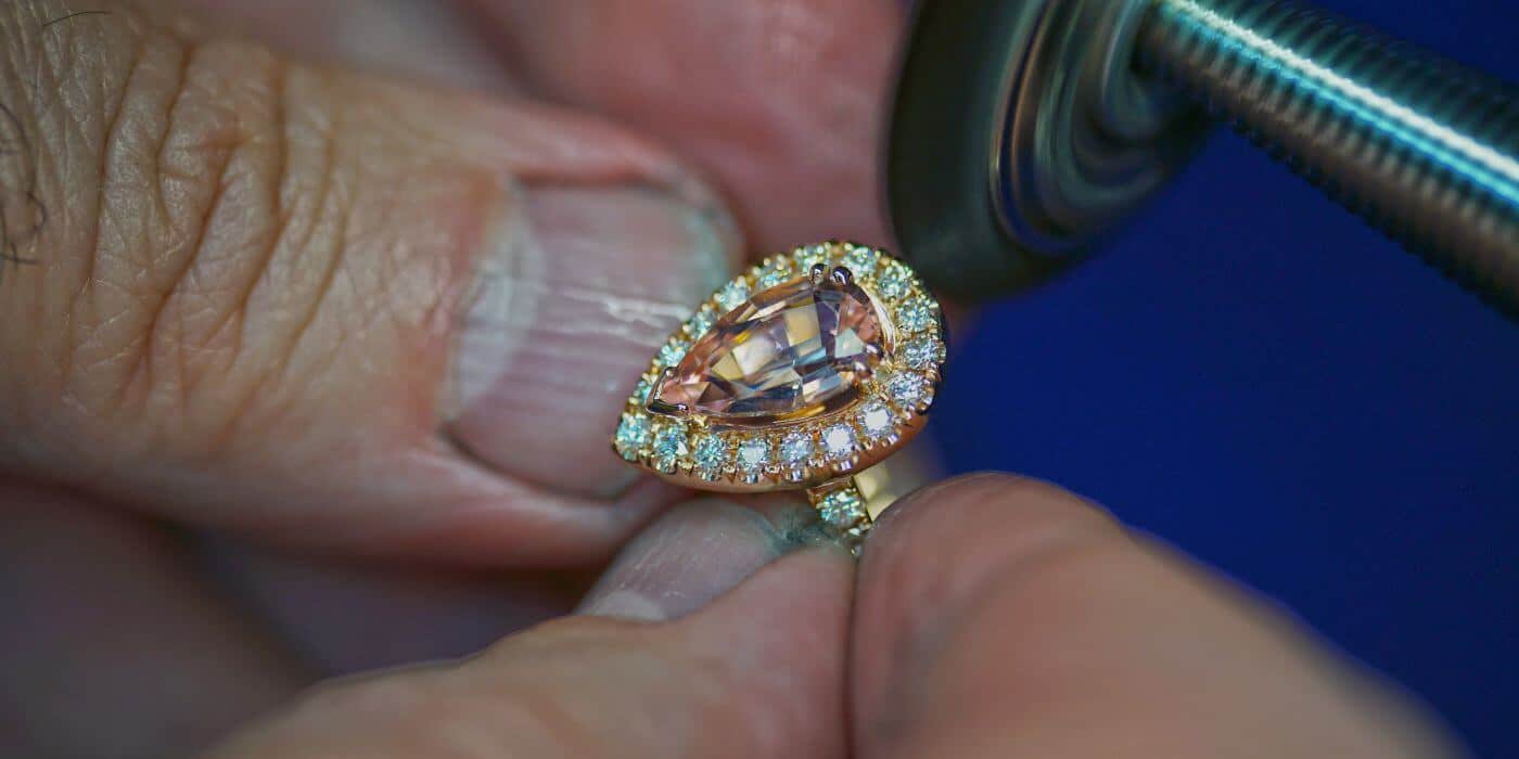 Someone holding and cleaning a pear shape halo ring